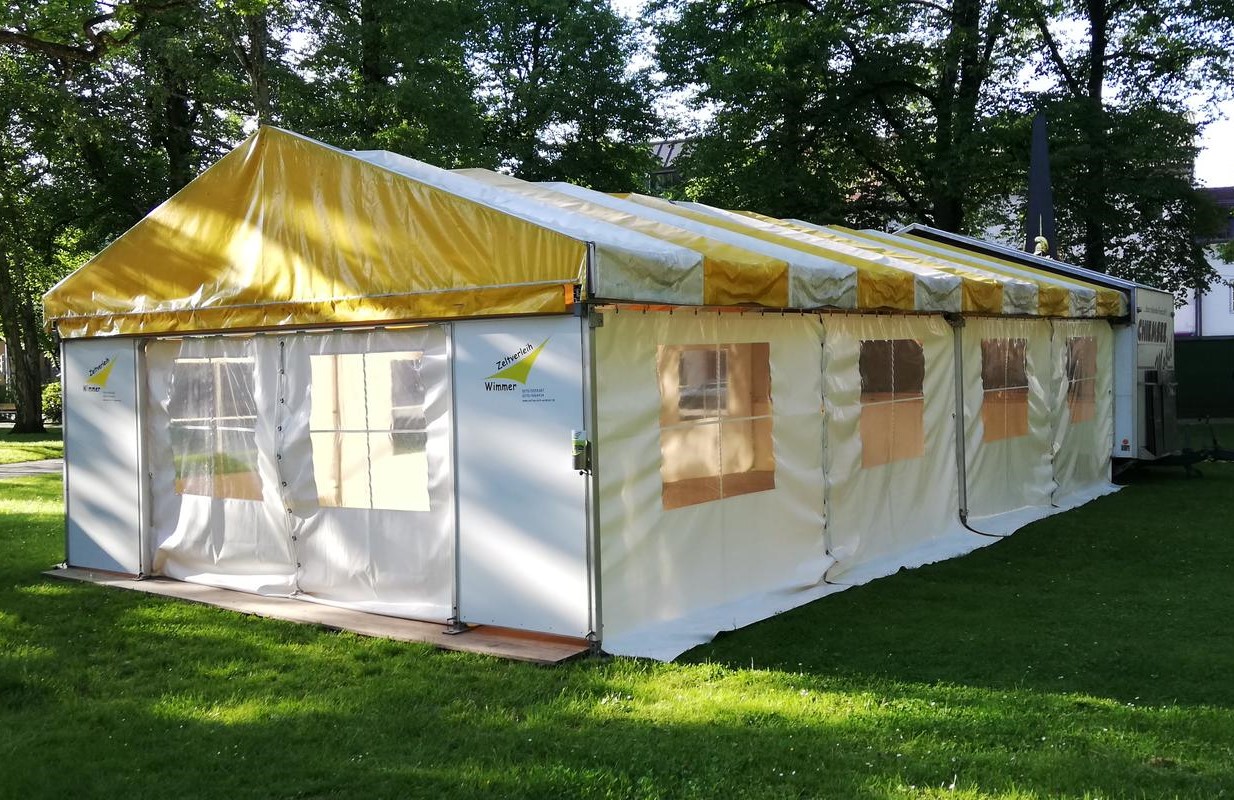 Chiemsee Mobil Zelt aufgebaut in Wiese mit Bäumen im Hintergrund